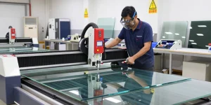 CNC glass cutting machine in operation, technician demonstrating precision glass cutting techniques